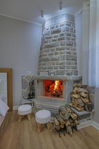 a stone fireplace with two stools and a fire place at Vila 1 in Korçë