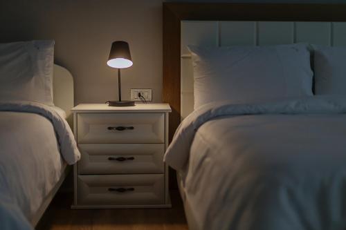a bedroom with two beds and a lamp on a night stand at Vila 1 in Korçë