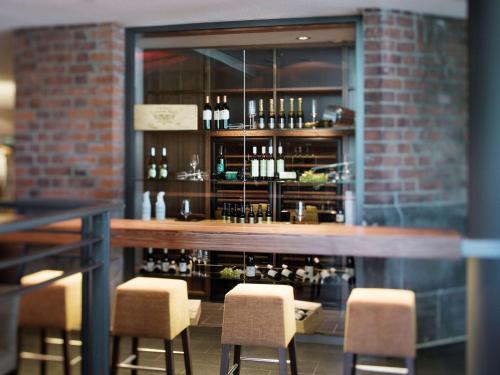 a bar with three chairs and a brick wall at Mövenpick Hotel Hamburg City in Hamburg