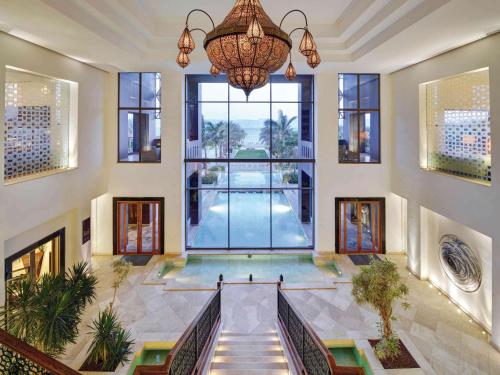 a large lobby with a large window and a chandelier at Mövenpick Resort & Spa Tala Bay Aqaba in Aqaba