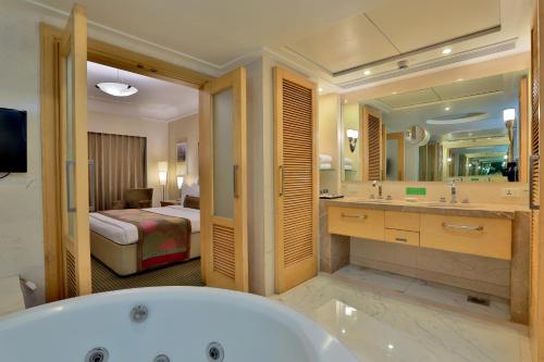 a bathroom with a bath tub and a bedroom at The Imperial Palace in Rajkot