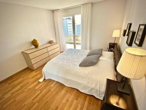 Spacious and bright 2 bedroom apartment with terrace في لوزان: غرفة نوم بيضاء بها سرير ونافذة