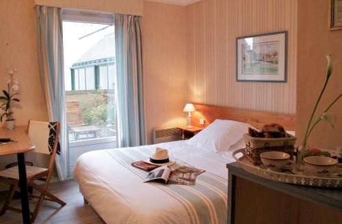 a bedroom with a bed with a window and a table at Hotel Sully in Nogent-le-Rotrou