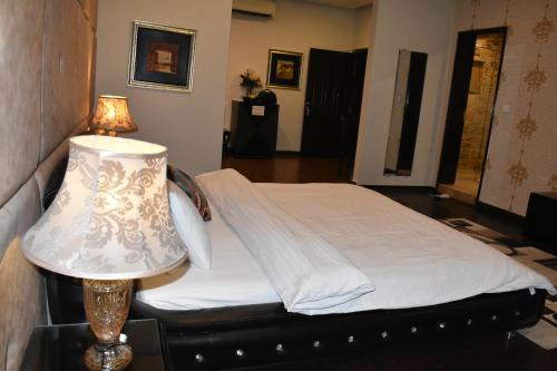 a bedroom with a bed with a lamp on a table at Safari Club 1 in Rawalpindi