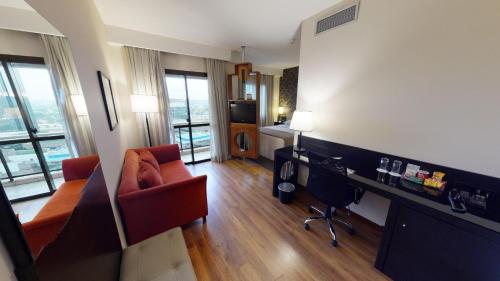 a living room with a couch and a desk in a room at Estanplaza Funchal Faria Lima in Sao Paulo