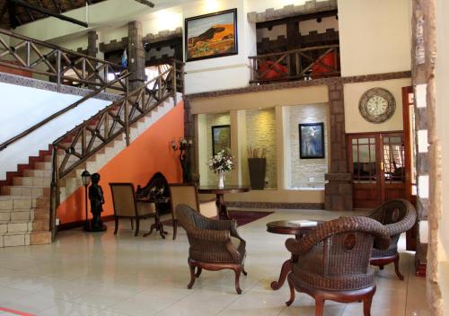 a lobby with a staircase and chairs and a table at Prinshof Manor Guesthouse in Pretoria