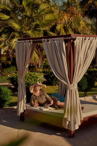 a woman sitting on a bed with a canopy at Grand Hyatt Doha Hotel & Villas in Doha