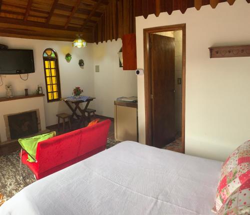 a bedroom with a bed and a living room at Chalés Lua de Mel in Monte Verde