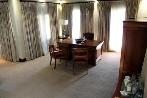 a room with a desk with two chairs and a lamp at Prinshof Manor Guesthouse in Pretoria