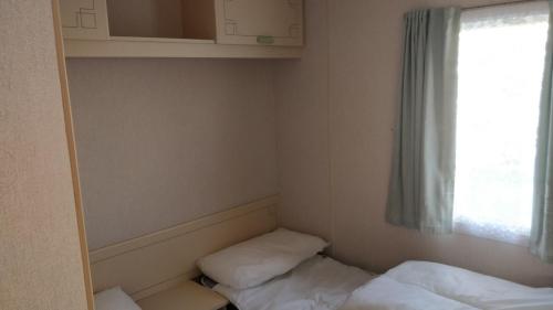 a small room with two beds and a window at 8 Berth Northshore Skegness The Cottage Panel heated in Lincolnshire