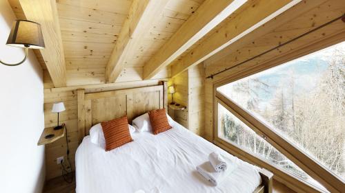 a bedroom in a tree house with a large window at Ann LANDSCAPED & LUXE chalet 8 pers by Alpvision Résidences in Nendaz