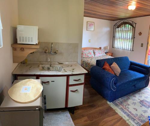 a bedroom with a couch and a sink and a bed at Chalés Lua de Mel in Monte Verde