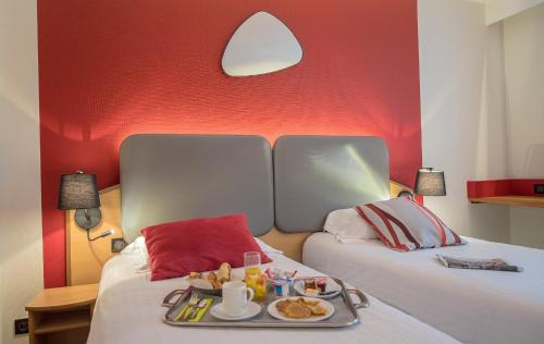 a hotel room with two beds with a tray of food at Promotel in Carros