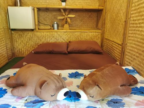 a brown teddy bear laying on a bed at ข้าวทุ่งเบ็ญจาโฮมสเตย์ in Ban Hat Phang