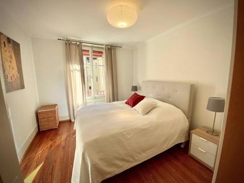 a bedroom with a white bed with a red pillow at Your bright charming cocoon between lake and city in Lausanne