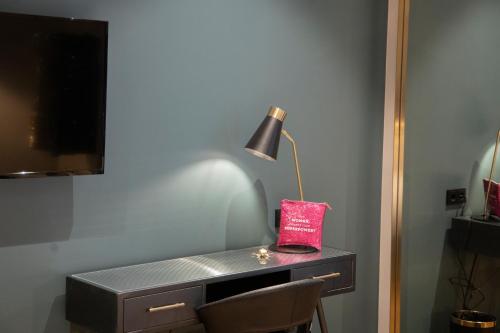 a desk with a lamp and a red bag on it at Munich Rooms Hotel in Munich