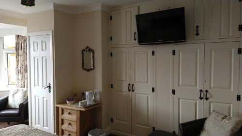 a living room with white cabinets and a flat screen tv at Hollingworth Lake Guest House Room Only Accommodation in Littleborough