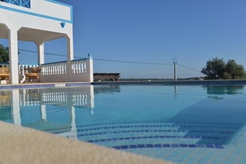 a swimming pool with a bench next to a house at Quinta da Fonte em Moncarapacho in Moncarapacho