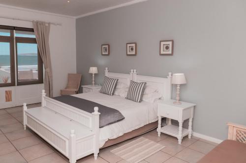 a white bedroom with a white bed and a window at Paternoster Lodge in Paternoster