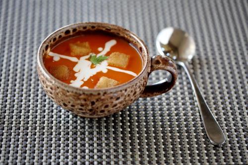a cup of soup with a spoon next to it at Hotel Kasturi Orchid in Pāl