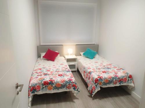 two beds in a small room with two colorful pillows at Guanarteme Vista Surf in Las Palmas de Gran Canaria