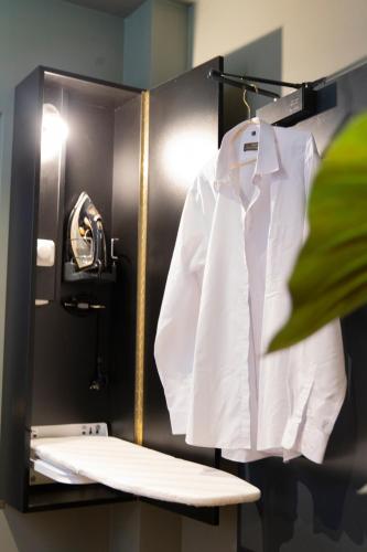 a white shirt hanging on a rack in a bathroom at Munich Rooms Hotel in Munich