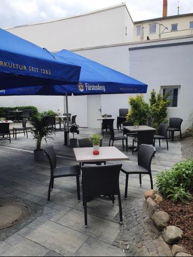 a patio with tables and chairs and a blue umbrella at Hotel Ritter St. Georg in Braunschweig