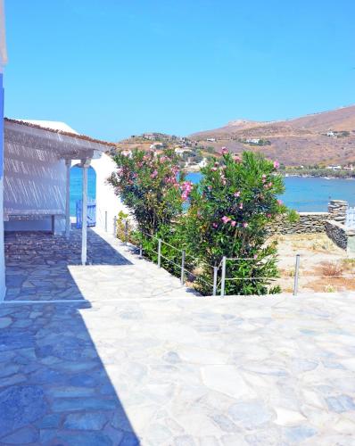 a stone walkway next to a building with trees and water at The charming Beach House, ideal for 4 to 5 people in Ioulida