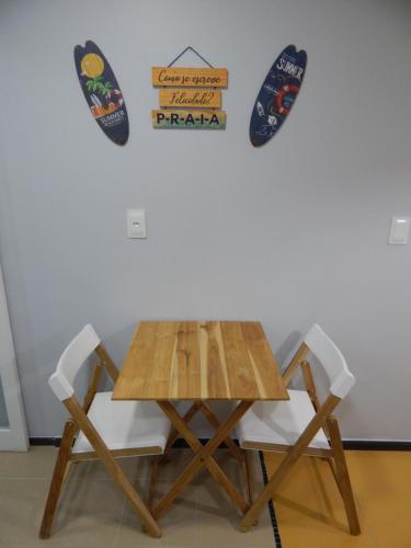 a wooden table and two chairs with signs on the wall at Varandas da Praia do Forte - Apartamento frente ao Mar in Cabo Frio