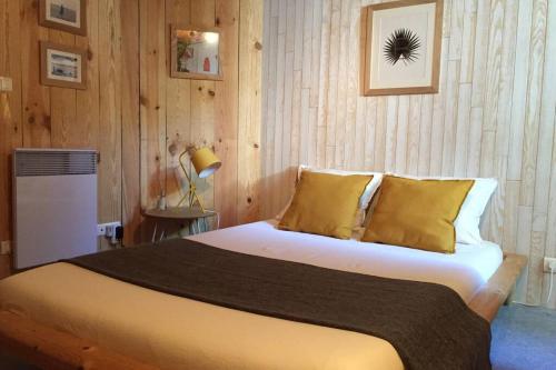 une chambre avec un grand lit avec des oreillers jaunes dans l'établissement Charme assuré pour ce logement idéalement situé, à Arcachon