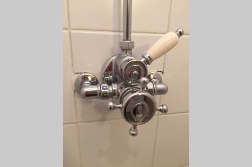 La salle de bains est pourvue d'une pomme de douche et de carrelage blanc. dans l'établissement Charme assuré pour ce logement idéalement situé, à Arcachon