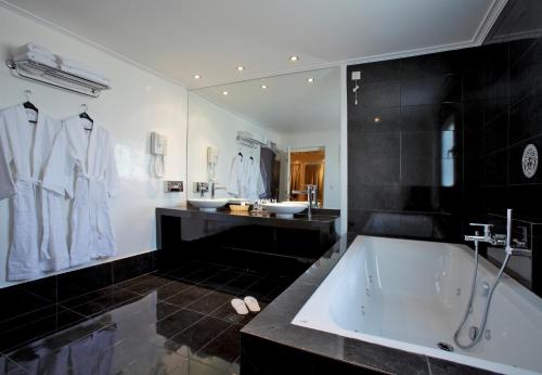 un bagno in bianco e nero con vasca e lavandini di Piraeus Theoxenia Hotel a Pireo