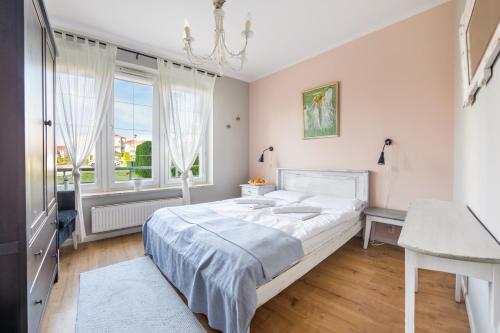 um quarto branco com uma cama e uma janela em Apartamenty Sun & Snow Bałtyk Park Grzybowo em Grzybowo