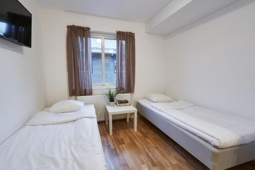two beds in a room with a table and a window at Bålsta Apartment Hotel in Bålsta