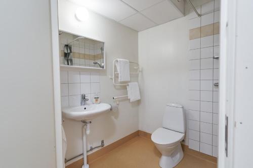 a white bathroom with a toilet and a sink at Bålsta Apartment Hotel in Bålsta