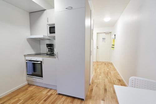 a kitchen with white walls and a wooden floor at Bålsta Apartment Hotel in Bålsta