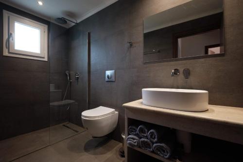 a bathroom with a sink and a toilet and a mirror at Olive Garden Studios & Apartments in Acharavi