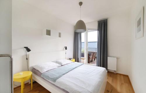 a white bedroom with a bed and a yellow table at Mountain Apartment Vrchlabi in Vrchlabí