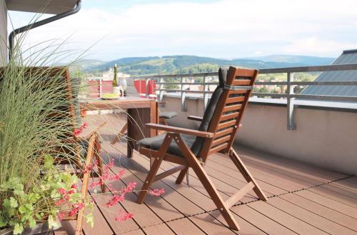a wooden chair sitting on a balcony with a table at Mountain Apartment Vrchlabi in Vrchlabí