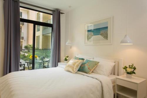 een slaapkamer met een wit bed en een groot raam bij Embassy Gardens Luxury Apartments in Accra