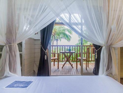 a bedroom with a bed and a balcony with a table at Carre Royal in Deshaies