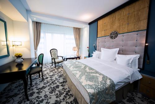 a hotel room with a large bed and a desk at Pleiada Boutique Hotel & Spa in Iaşi