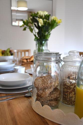 a table with jars of food and a vase of flowers at Friarscroft Lodge Holiday Home in Wymondham