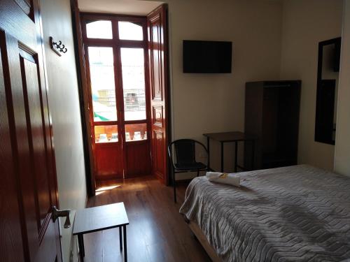 a bedroom with a bed and a window and a door at Casona Hotel in Pasto