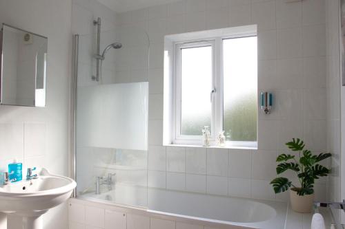 a white bathroom with a sink and a tub and a window at Friarscroft Lodge Holiday Home in Wymondham