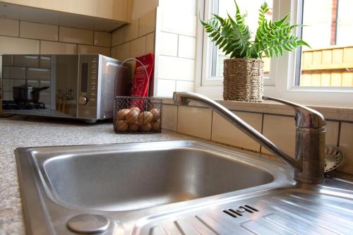 a stainless steel sink in a kitchen with a microwave at Friarscroft Lodge Holiday Home in Wymondham
