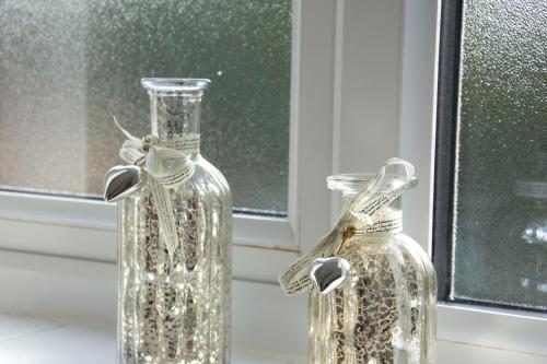 two clear glass bottles sitting on a window sill at Friarscroft Lodge Holiday Home in Wymondham
