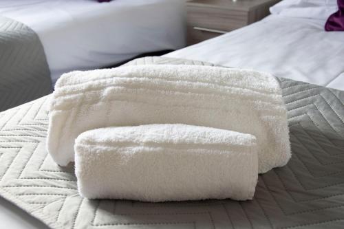 two white towels sitting on top of a bed at Friarscroft Lodge Holiday Home in Wymondham