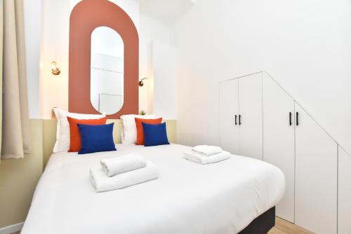 a bedroom with a large white bed with blue and orange pillows at CMG Condorcet / Lentonnet 3 in Paris