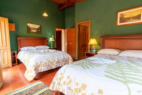 two beds in a room with green walls at La Posada Del Arte in Baños